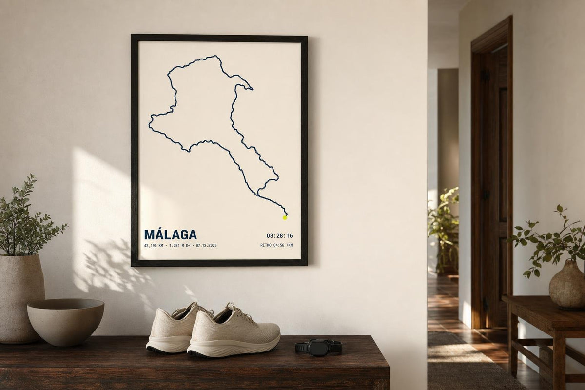 Cuadro con el recorrido de una maratón en Málaga colgado en la pared de una entrada, junto a zapatillas y un reloj deportivo.