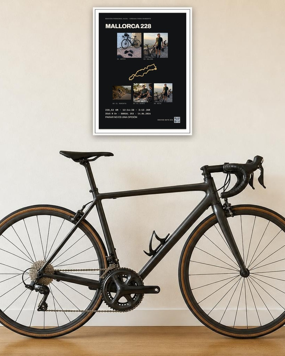 Cuadro de ciclismo personalizado con marco blanco, colgado sobre una bicicleta de carretera en el recibidor de una casa.
