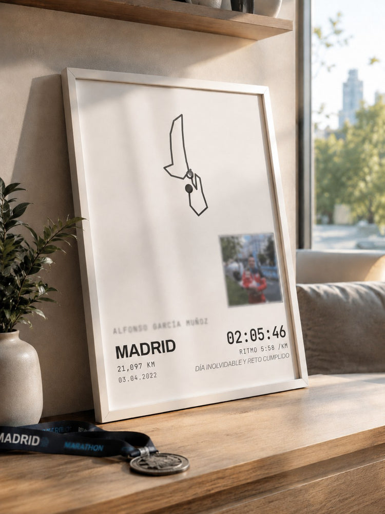 Cuadro Galería 30×40 real, enmarcado, con el recorrido de una media maratón en Madrid, apoyado junto a la medalla en un mueble de madera.