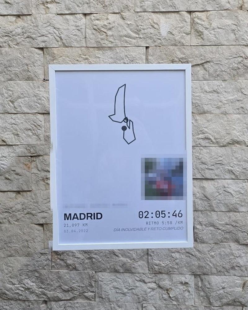 Cuadro de running con marco blanco colgado en una pared de piedra